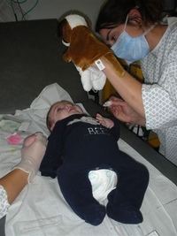Une infirmière distrait un bébé hospitalisé avec une marionnette pendant le soin