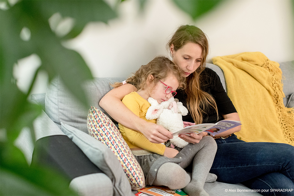 Maman lisant un guide SPARADRAP avec sa fille.