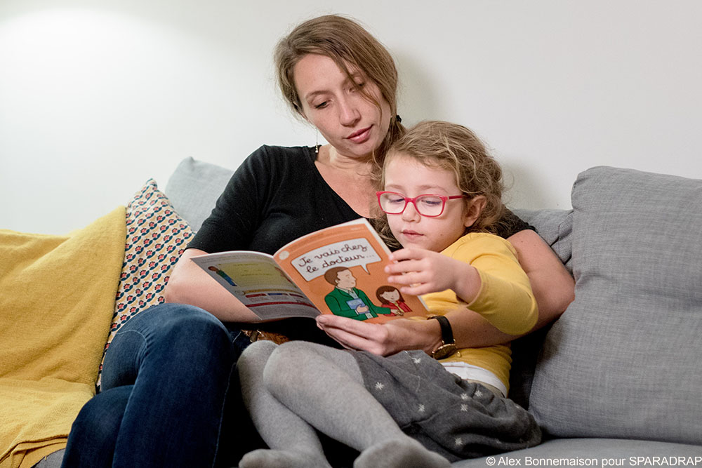 Une maman et sa fille lisent le livret "Je vais chez le docteur"