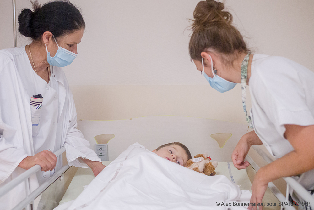 Deux soignantes veillent sur un enfant dans son lit d'hôpital