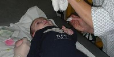 Une infirmière distrait un bébé hospitalisé avec une marionnette pendant le soin
